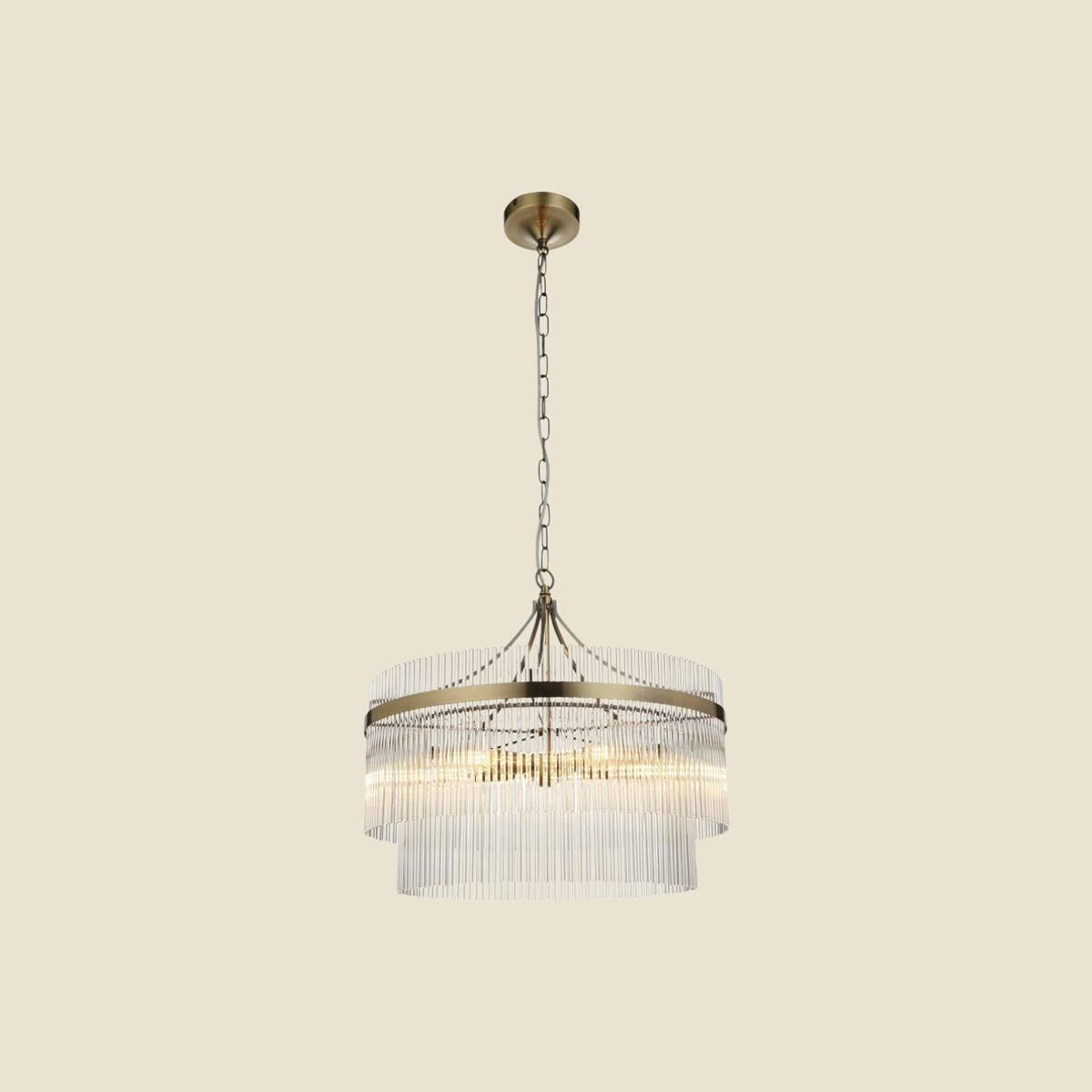 A modern two-tier cylindrical pendant chandelier with clear glass fringe and an antique brass frame, suspended by a chain from a matching ceiling canopy against a solid beige background.