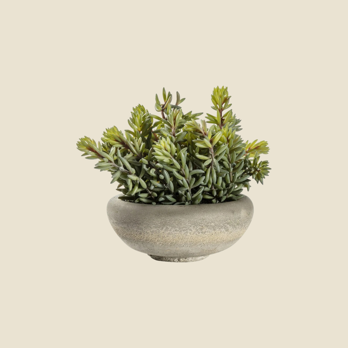 An artificial succulent plant with dense green and yellow-green leaves, potted in a round, textured gray concrete-style planter, shown against a solid light beige background.