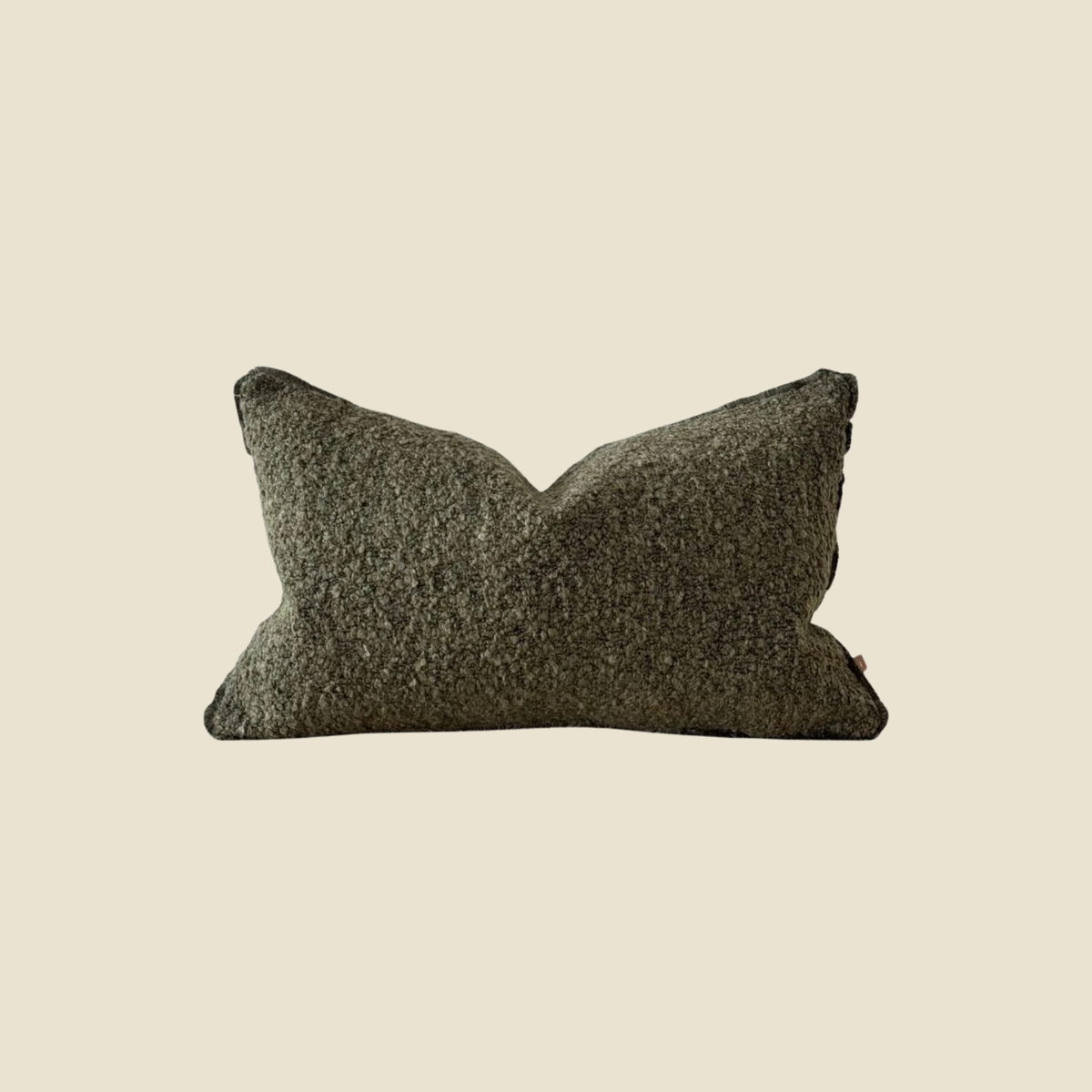 A rectangular lumbar pillow in a textured, heathered dark olive green fabric, centered against a solid cream-colored background.