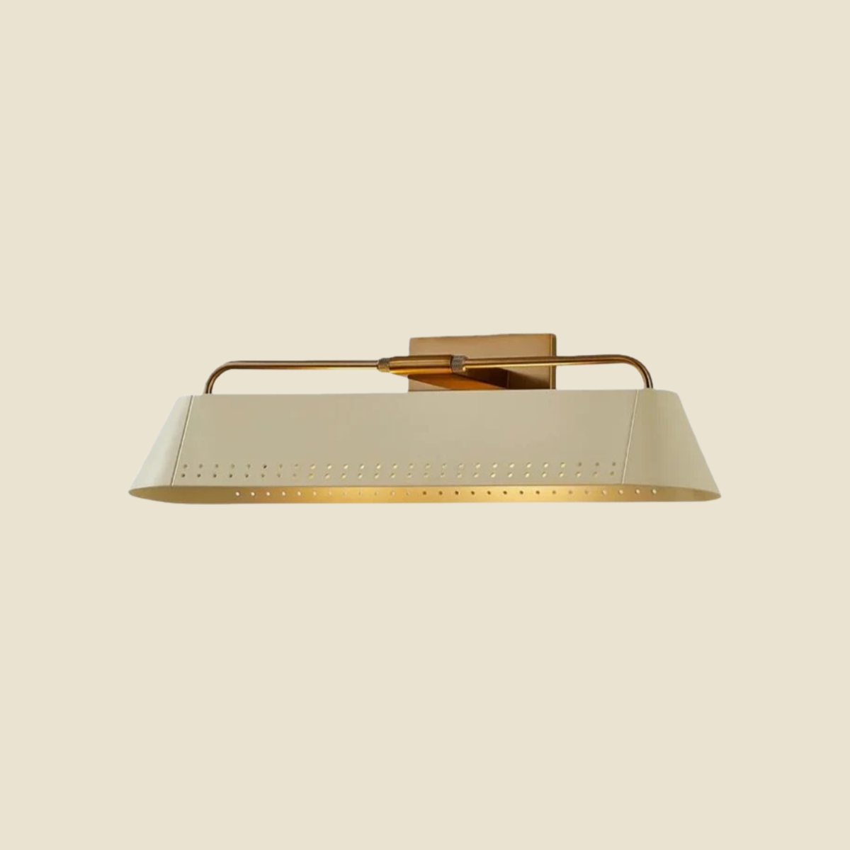 A modern wall-mounted light fixture with a tapered cream-colored metal shade featuring perforated detailing and a warm brass-toned horizontal arm and wall mount, shown against a solid cream background.