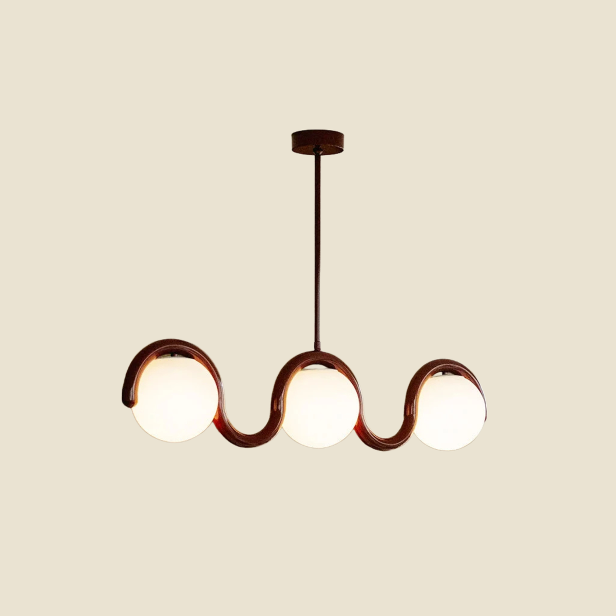 A modern three-light linear chandelier with a red wavy metal frame and glowing white frosted glass globes, suspended from a matching dark canopy against a solid beige background.