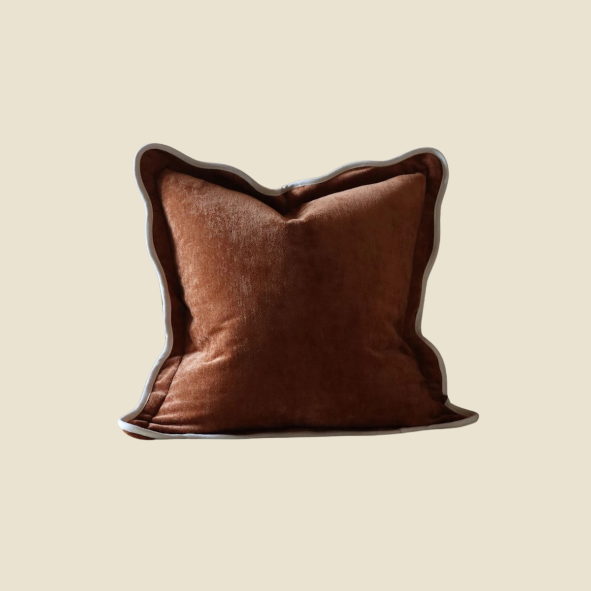 A square brown velvet throw pillow with a dark brown piped edge, centered on a solid beige background.