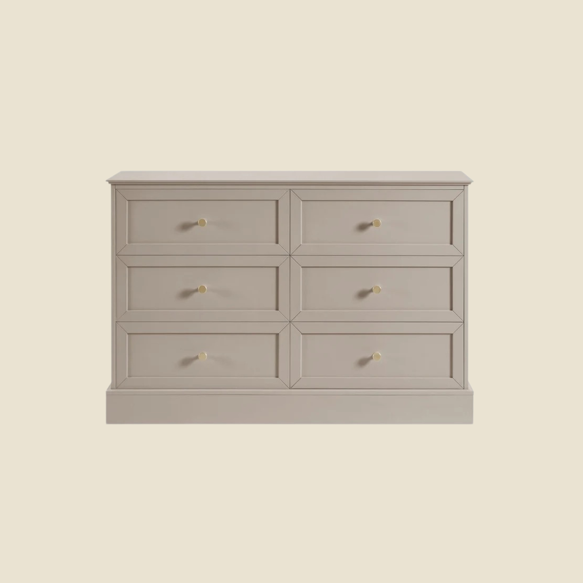 A six-drawer wooden dresser in a light grayish beige finish with small round gold knobs, shown against a solid cream background.